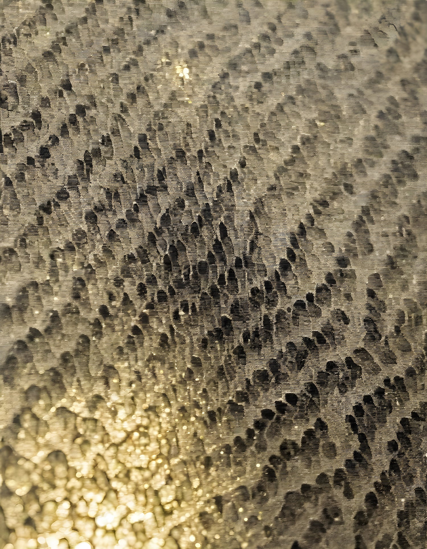 Textured metallic surface with intricate patterns reflecting light in a close-up shot during daylight