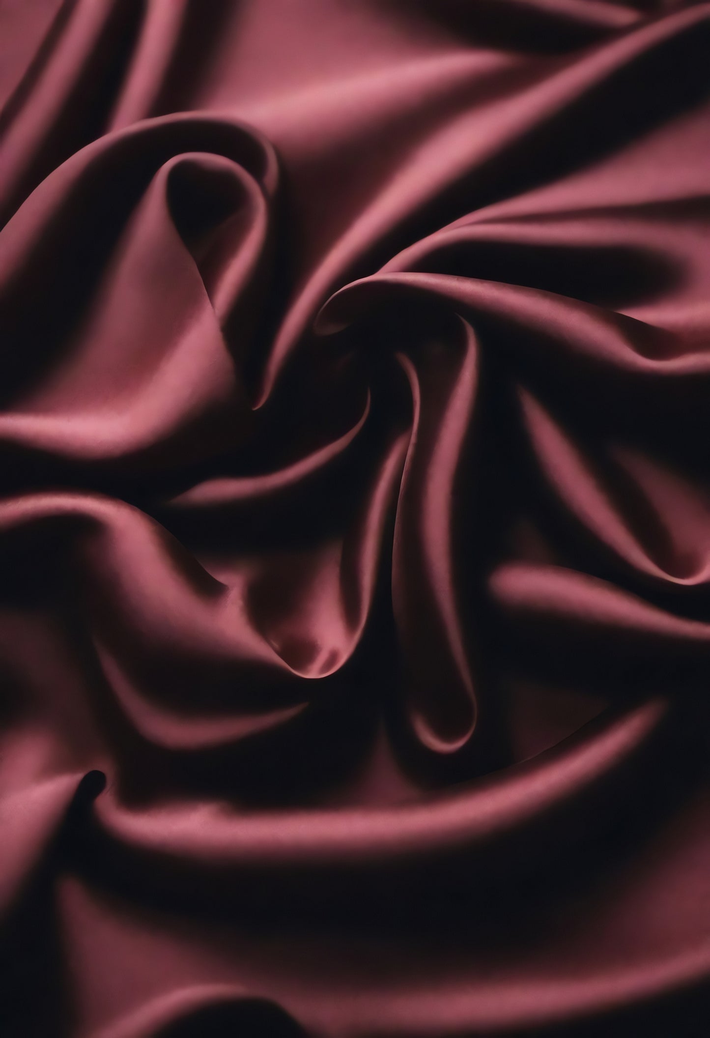 Rich burgundy satin fabric draping elegantly with smooth texture and soft folds captured in soft lighting