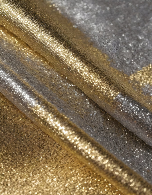 Metallic golden and silver fabric creates elegant textures with intricate folds and reflections under soft lighting