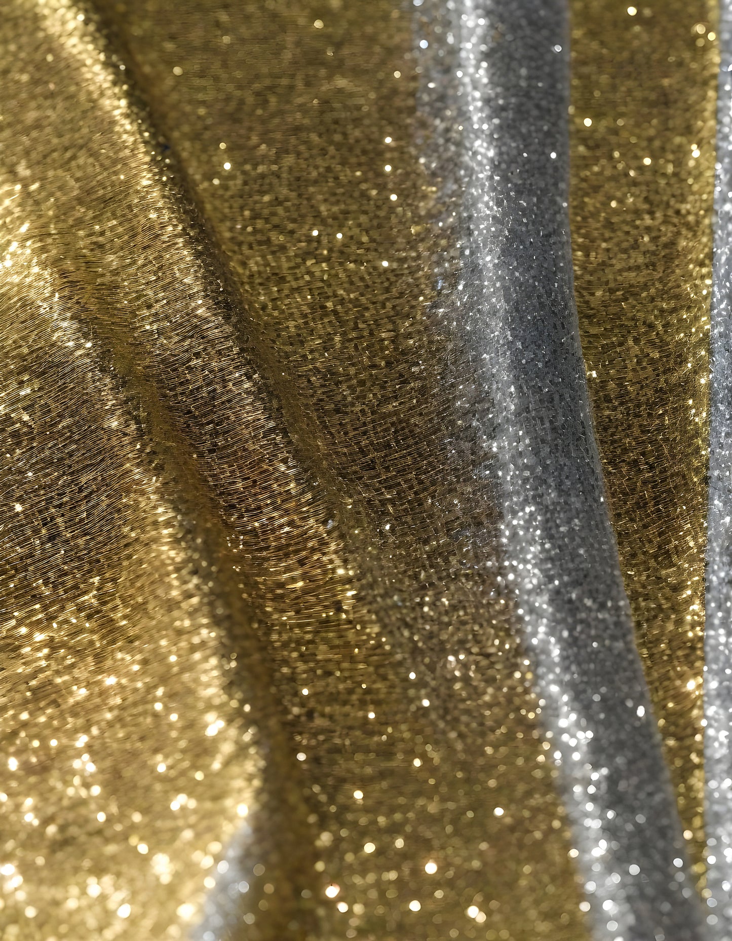 Metallic golden and silver fabric creates elegant textures with intricate folds and reflections under soft lighting