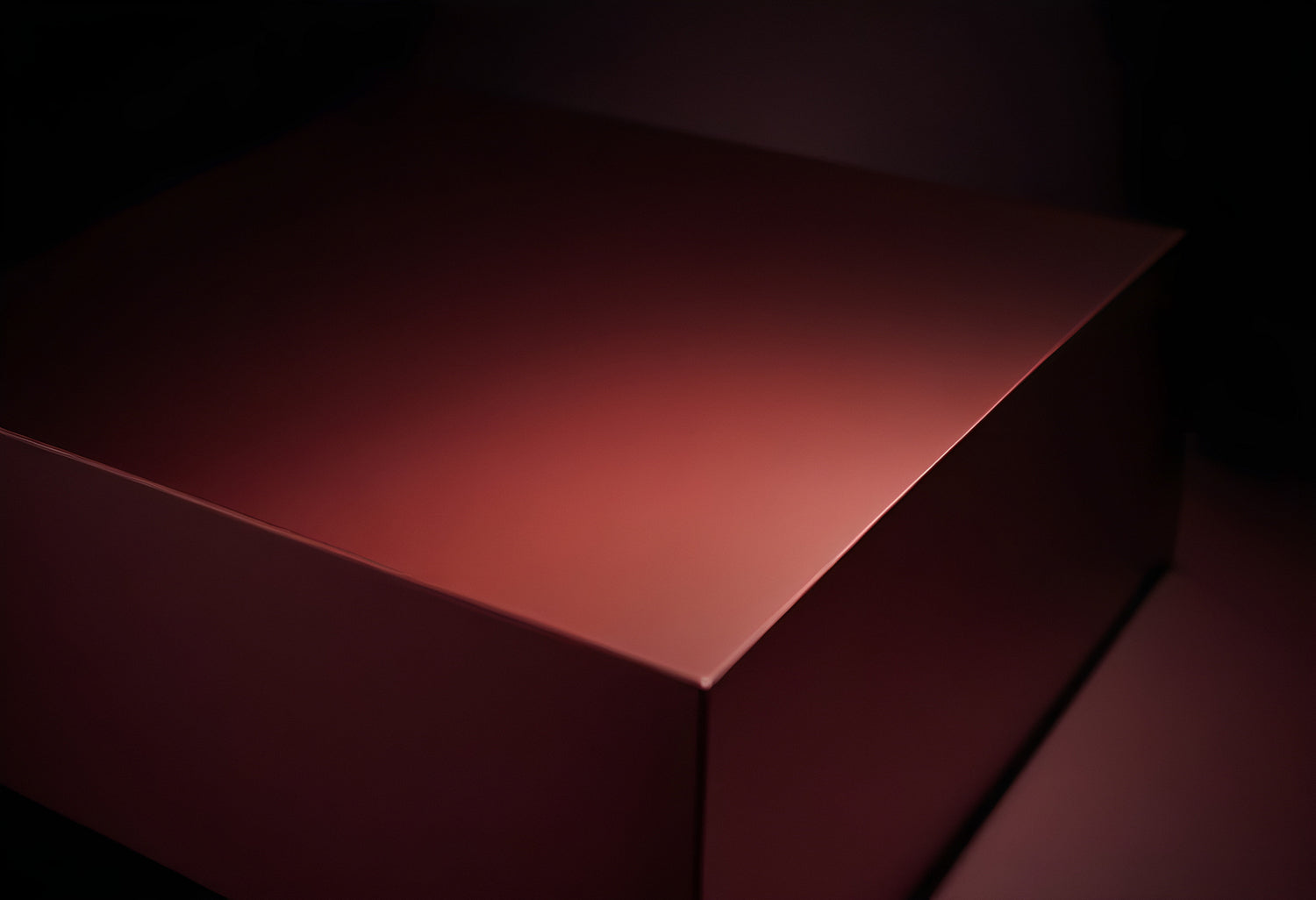 Close-up view of a smooth, red-brown box illuminated in soft lighting, creating an elegant ambiance on a dark background