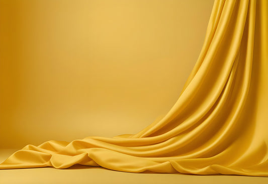 A soft yellow fabric drapes elegantly on a smooth surface, creating a warm and inviting atmosphere in the studio