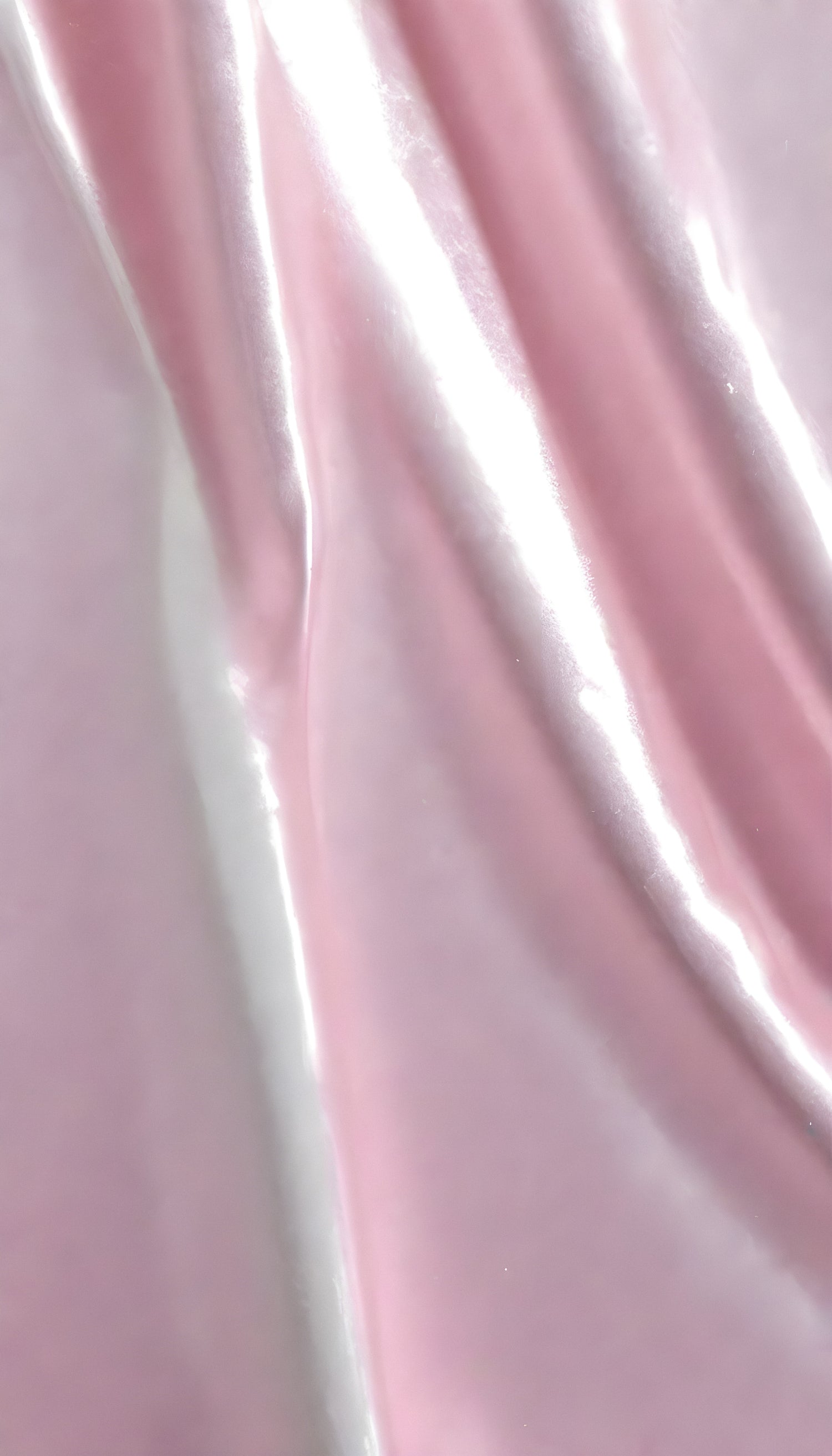 A close-up view of soft, shiny pink fabric draped elegantly, highlighting its smooth texture and sheen, perfect for luxurious designs