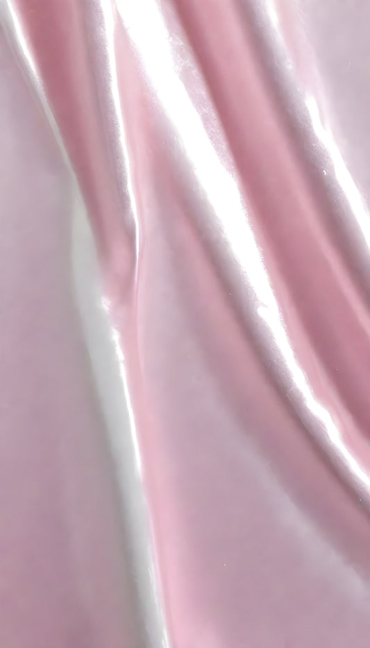 A close-up view of soft, shiny pink fabric draped elegantly, highlighting its smooth texture and sheen, perfect for luxurious designs