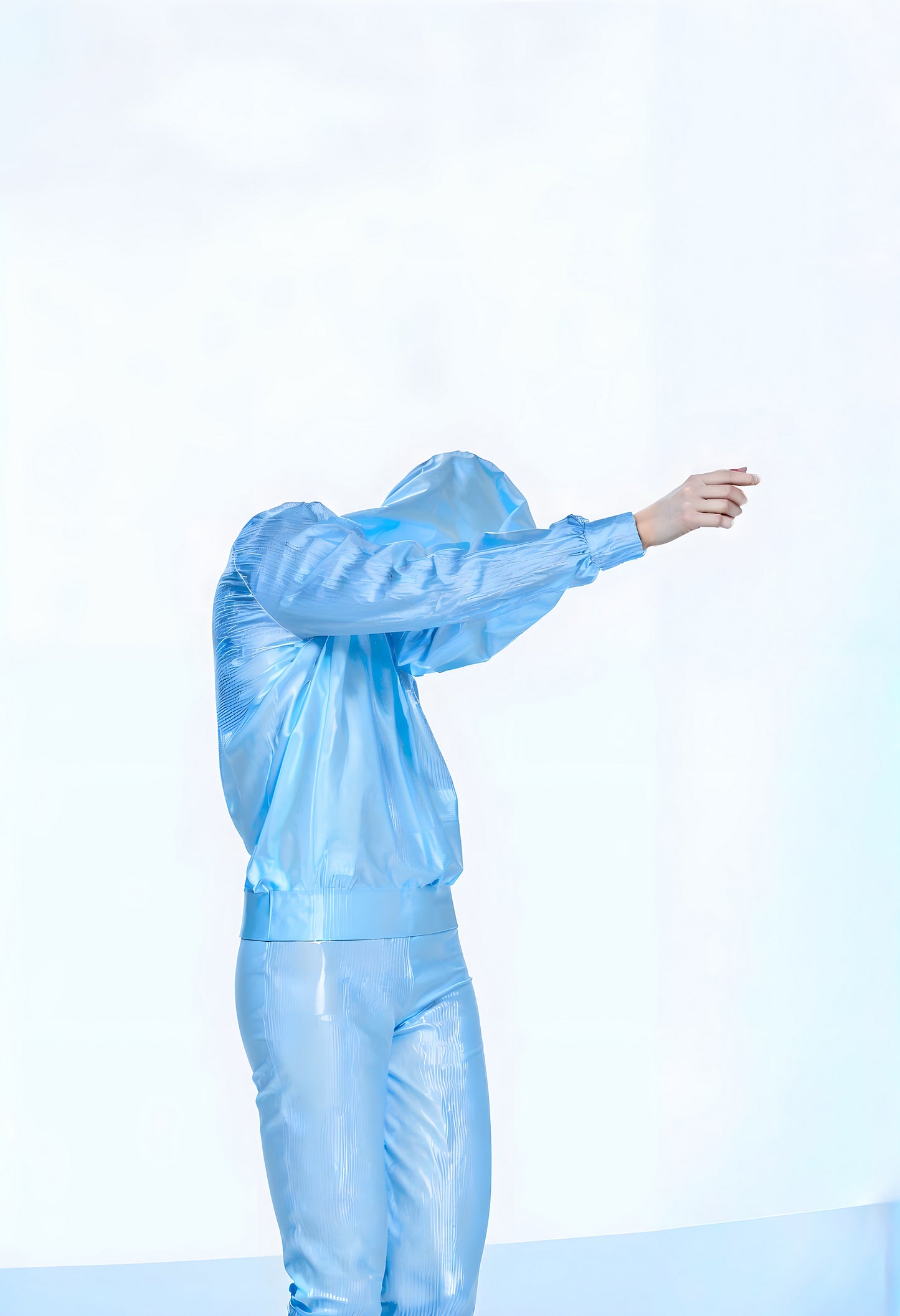 A figure in a blue reflective outfit gestures expressively against a minimalist background in a bright studio setting