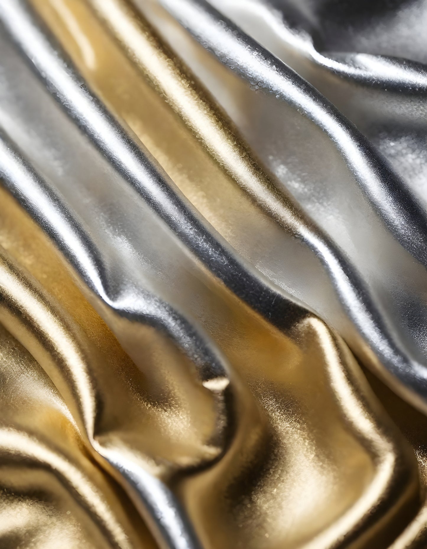 Metallic golden and silver fabric creates elegant textures with intricate folds and reflections under soft lighting