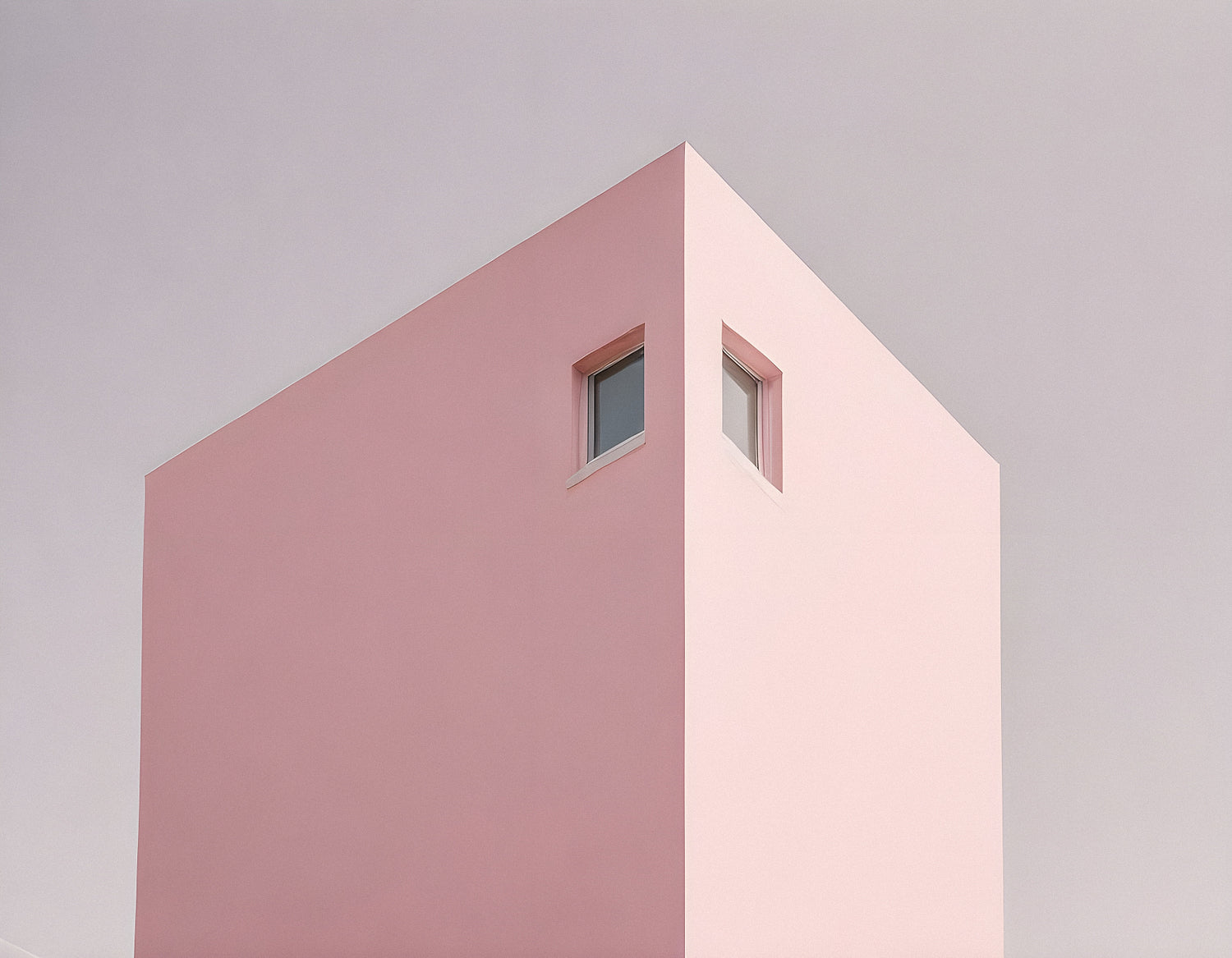 Modern architecture featuring a minimalist pink building with a single window against a clear sky in an urban setting