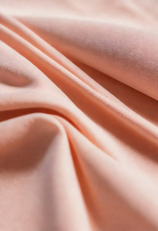 Soft peach fabric draped elegantly on a neutral background during daylight