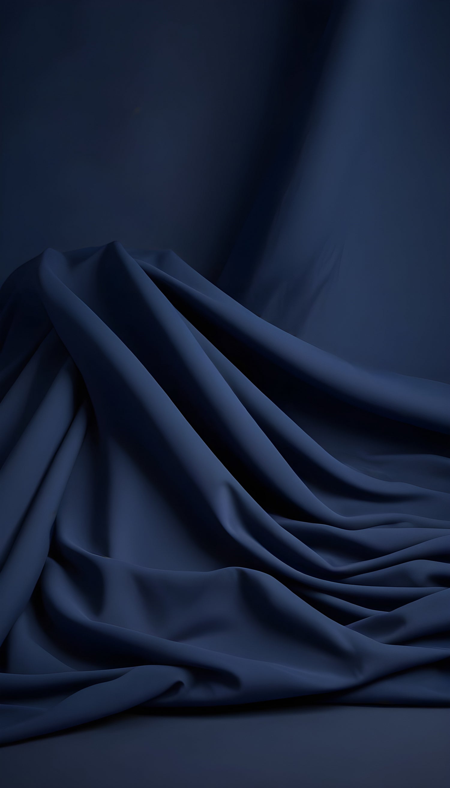 Elegant blue fabric drapes creating soft folds and shadows in a serene setting illuminated by gentle light