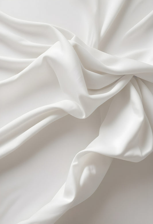 Soft white fabric draping elegantly across a smooth surface, showcasing light and texture in a minimalist setting