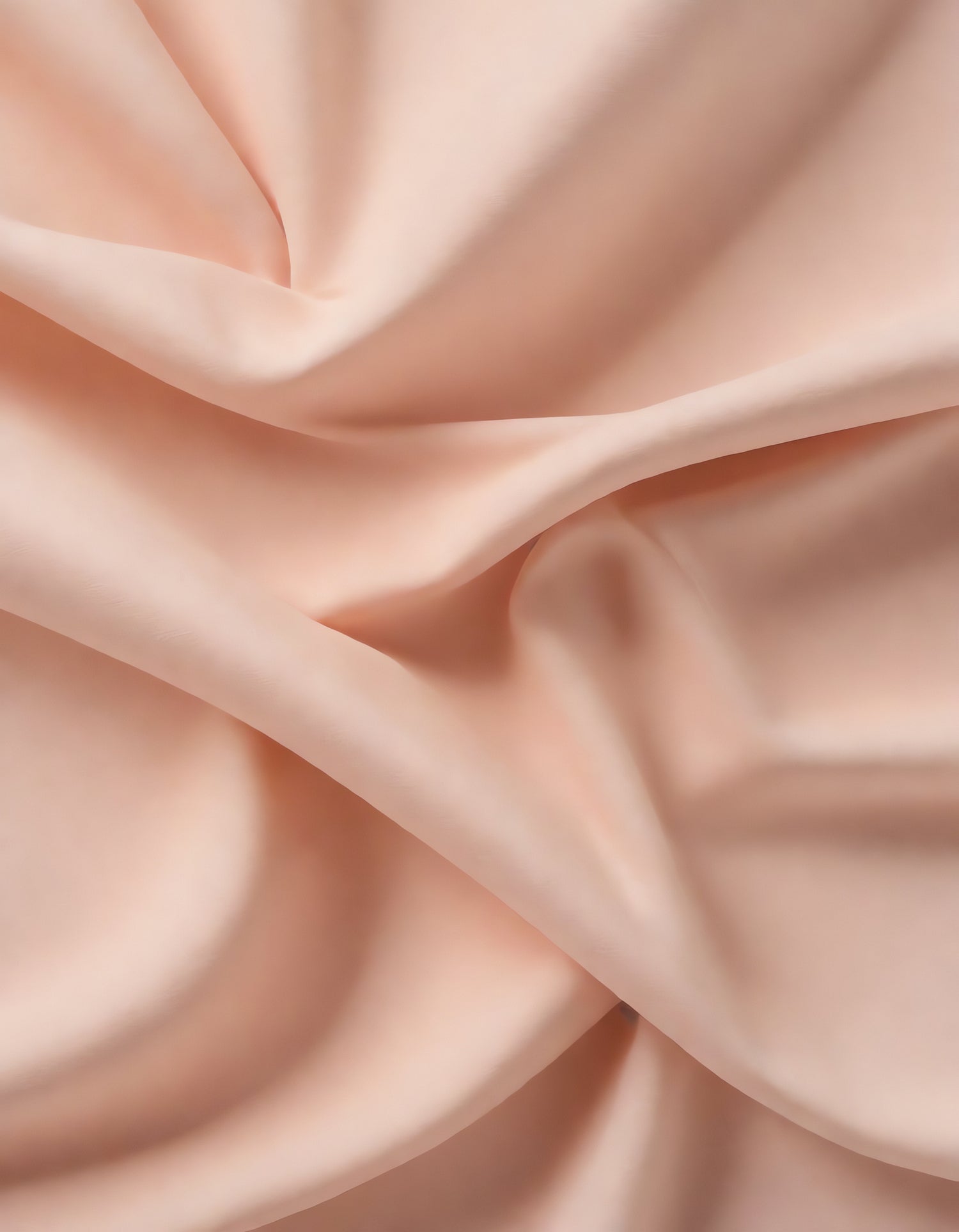 Soft peach fabric draped elegantly on a neutral background during daylight