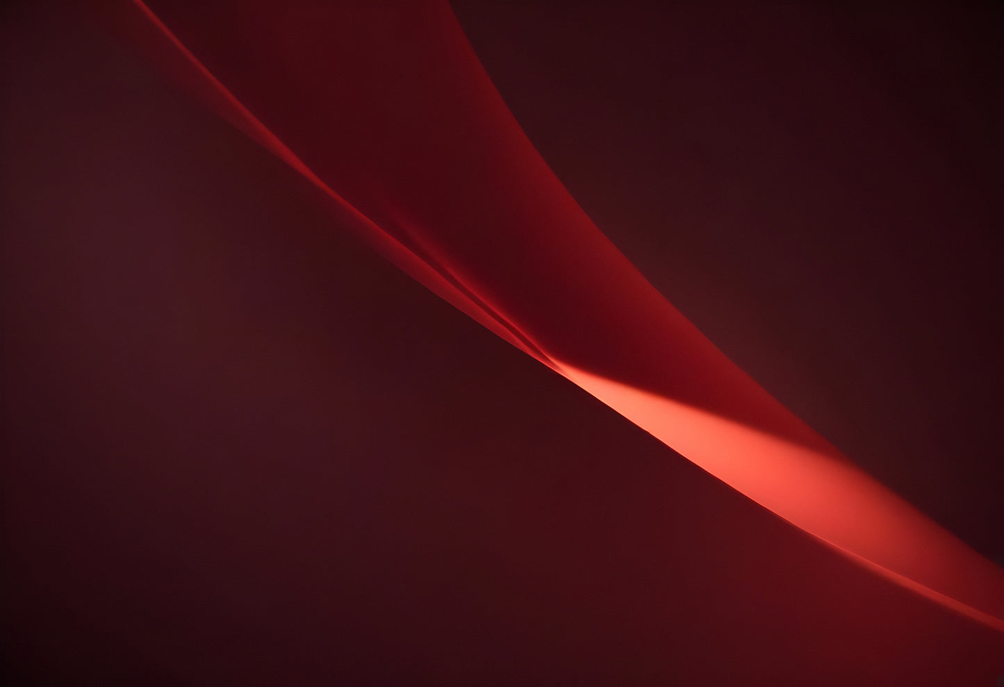 A soft glowing curve against a deep red background creates an abstract and calming visual experience in a minimalist setting