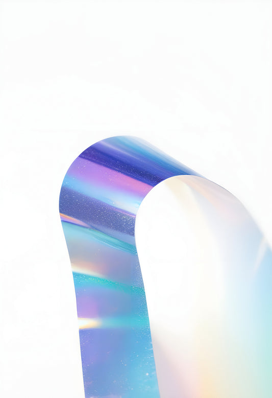 A translucent, colorful film curls gracefully against a soft white background, capturing light in delicate, rainbow-like reflections