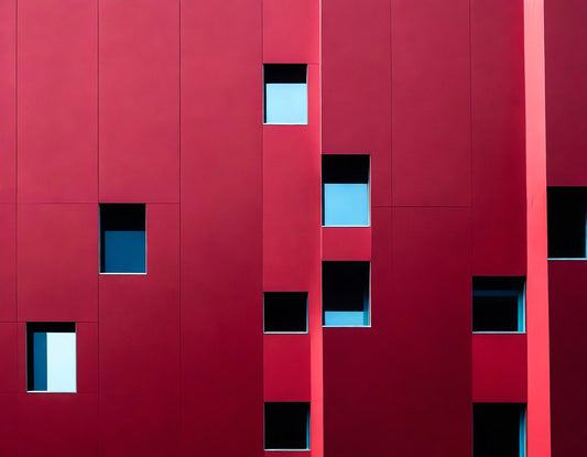 Red building facade with varying window shapes and sizes, showcasing modern architectural design in an urban environment