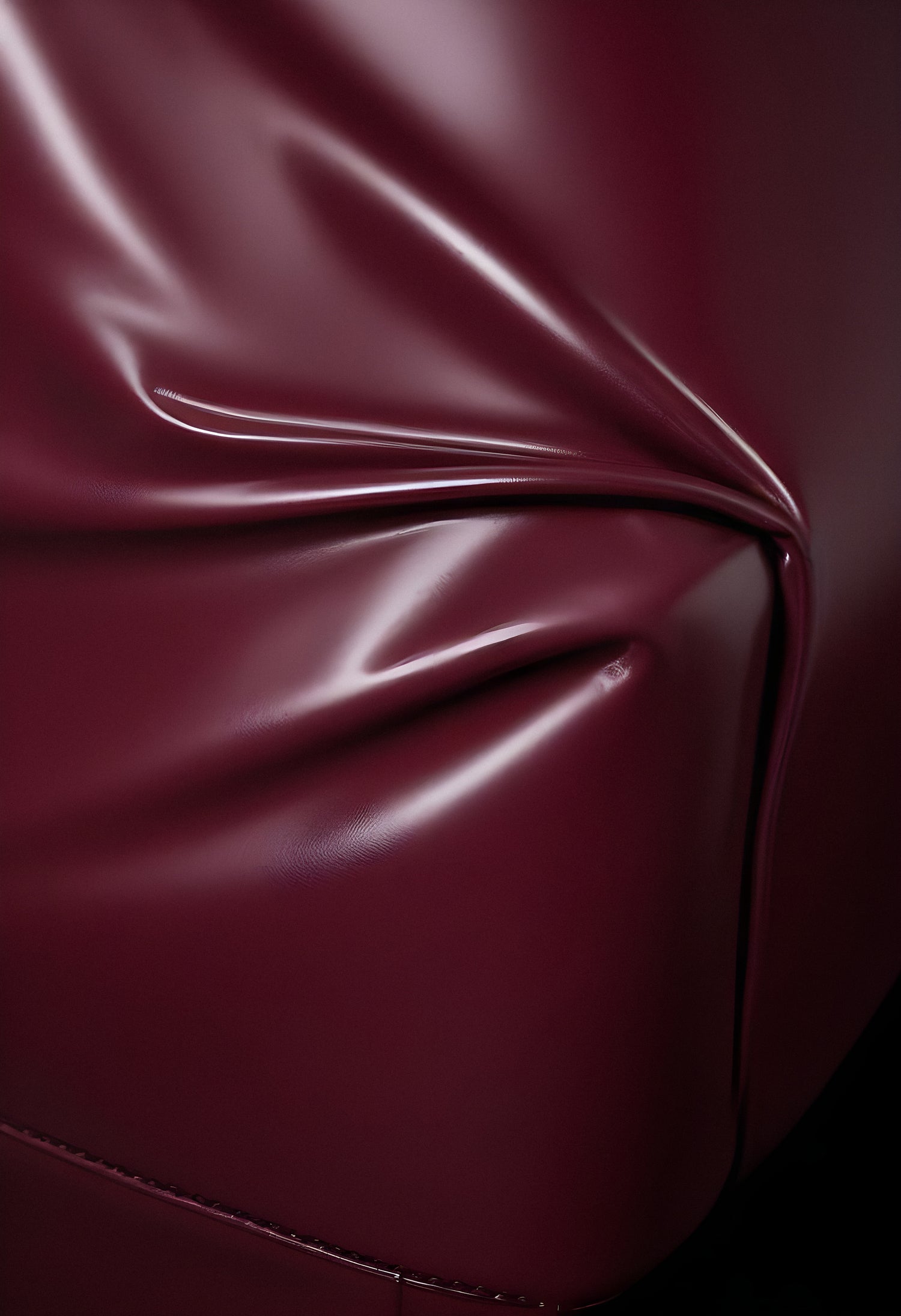 Deep maroon fabric draped elegantly on a surface, showcasing smooth texture and subtle shine in soft lighting