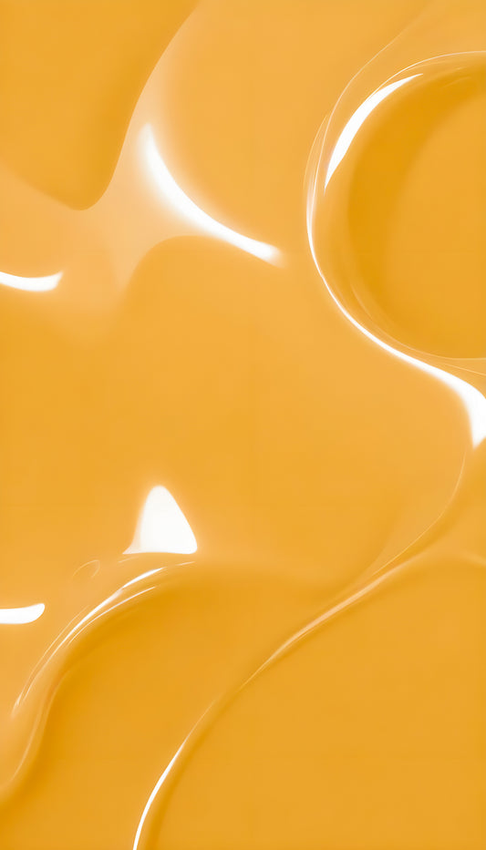 Glossy yellow liquid flowing smoothly across a surface, reflecting light in an artistic display of color and texture