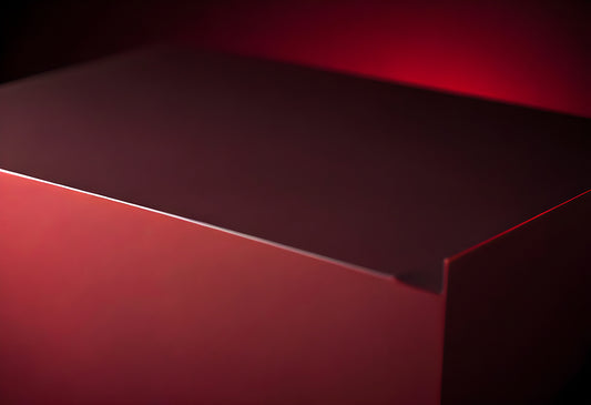 A close-up view of a sleek red box illuminated by soft lighting set against a darker background, emphasizing its smooth surface and shape