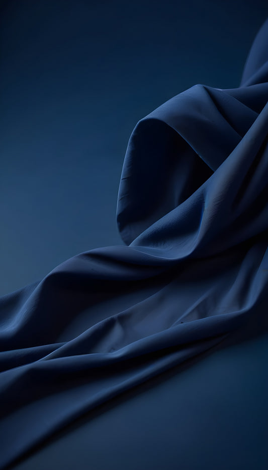 Elegant blue silk fabric draped gracefully against a deep blue backdrop in a soft, ambient lighting setting