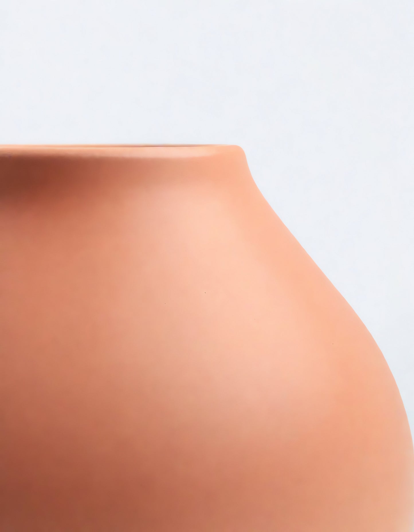 A close-up view of a handcrafted terracotta vase emphasizing its smooth curves and natural finish