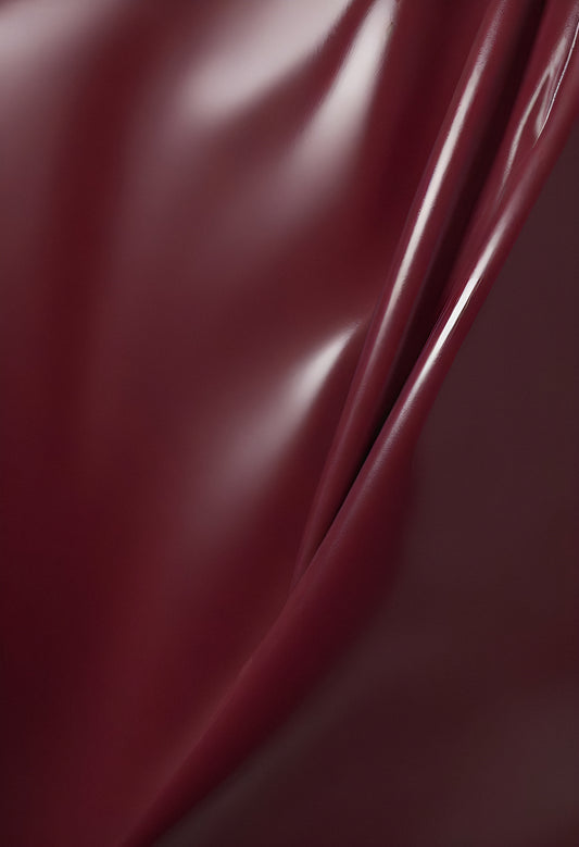 Deep maroon fabric draped elegantly on a surface, showcasing smooth texture and subtle shine in soft lighting