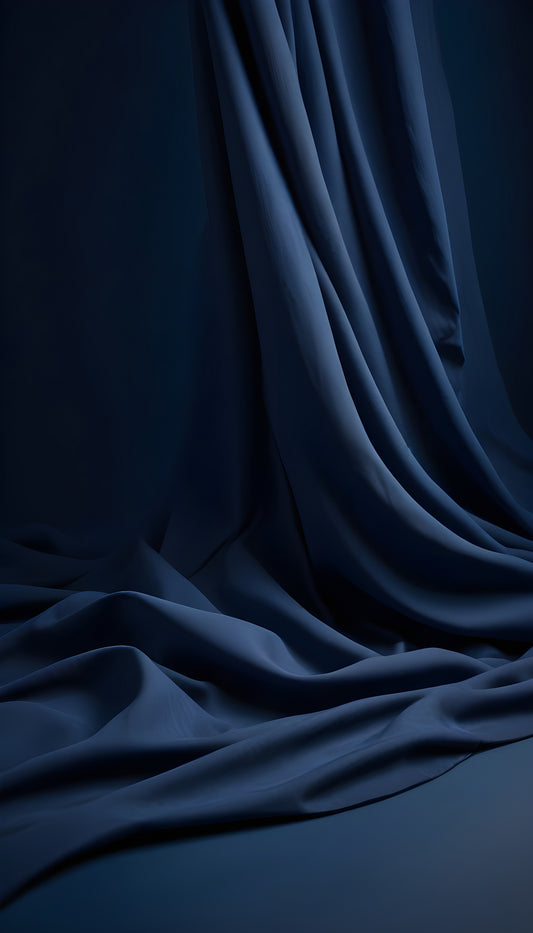 Elegant deep blue fabric draping gracefully against a dark backdrop, showcasing texture and depth in a minimalistic setting