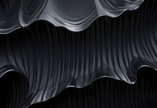 Black textured surface with flowing, wavy patterns illuminated in soft light