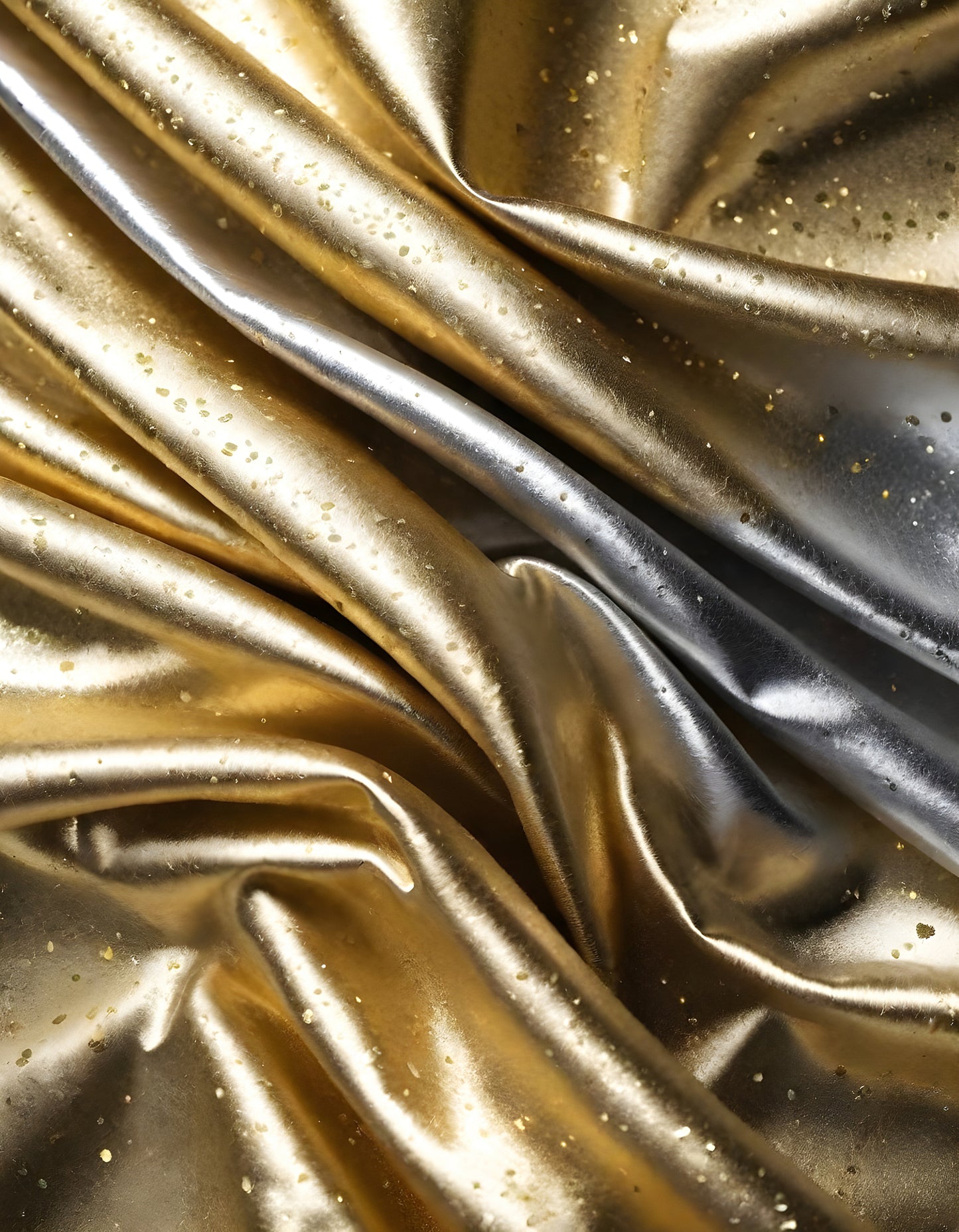 Metallic golden and silver fabric creates elegant textures with intricate folds and reflections under soft lighting