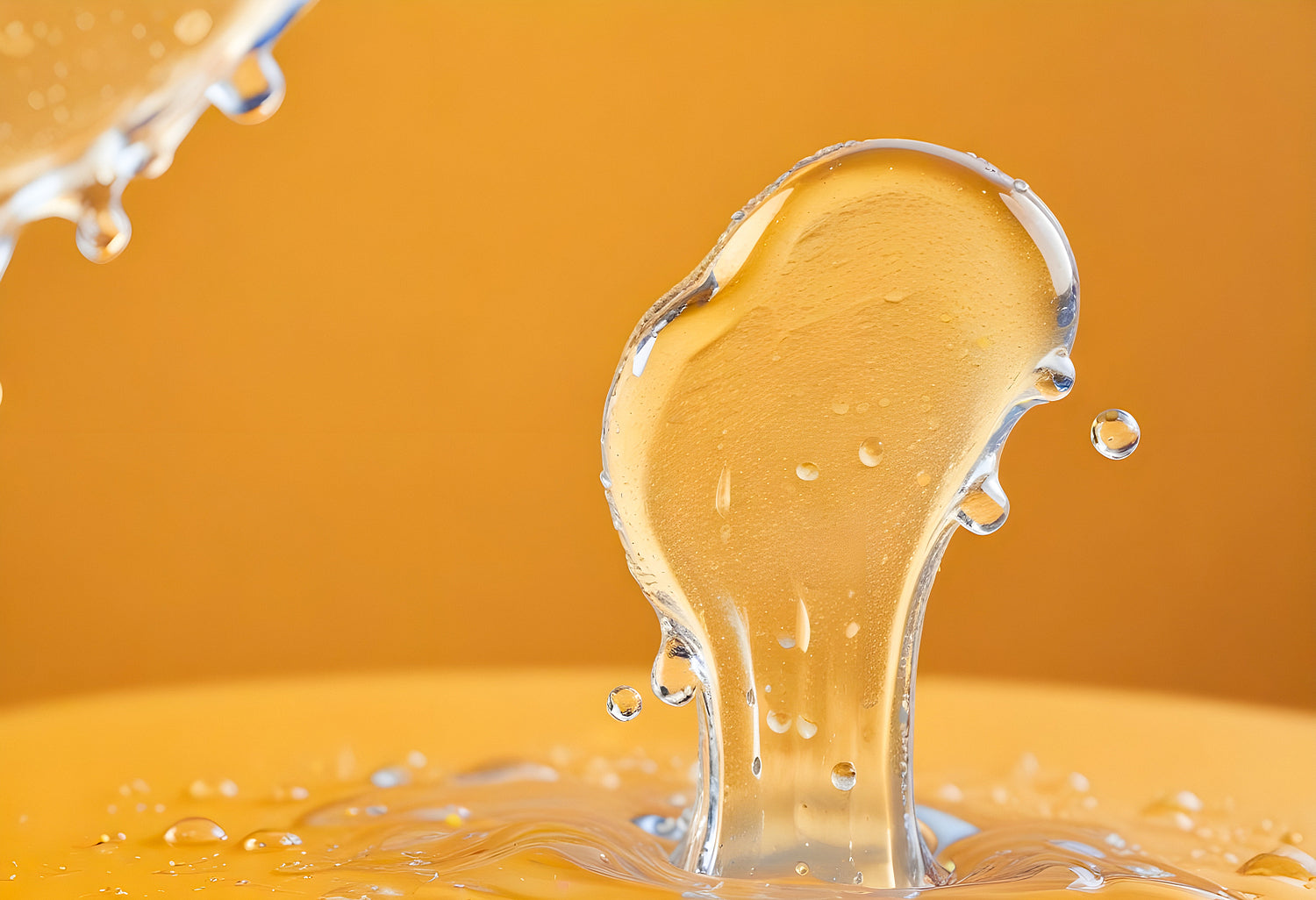 Clear water droplet splashing against a smooth surface, illuminated by warm lighting in a studio setting