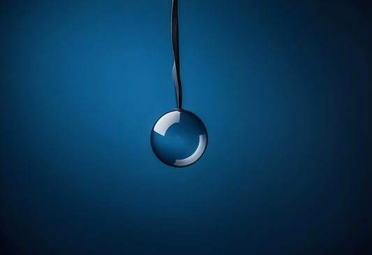 A glass ball suspended from a metal surface against a blue background