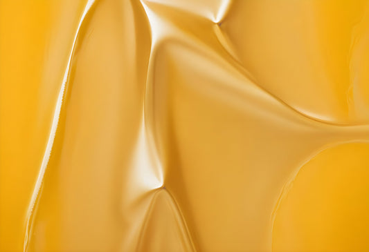 Smooth yellow texture with soft folds and reflections against a plain background captured in natural light