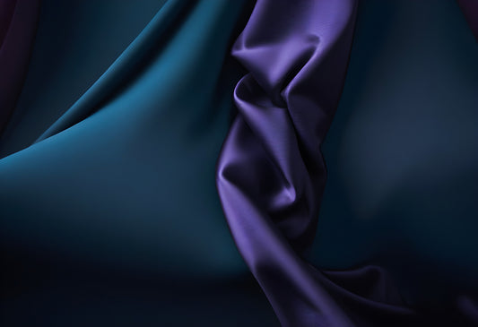 Close-up of elegantly draped fabric in shades of teal and purple, showcasing intricate textures and color interplay