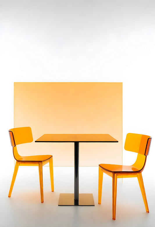 Modern transparent chair and table set against an orange backdrop in a minimalist interior design setting