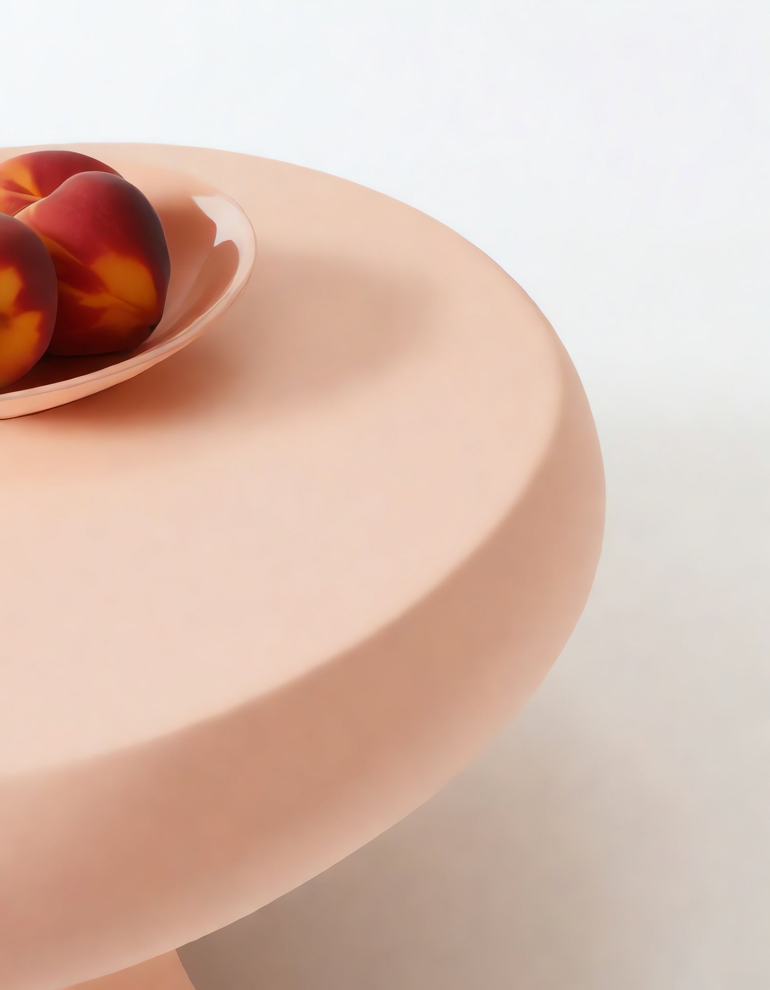 A minimalist peach-colored table featuring a shallow bowl with three ripe peaches in natural light, creating a serene dining setting