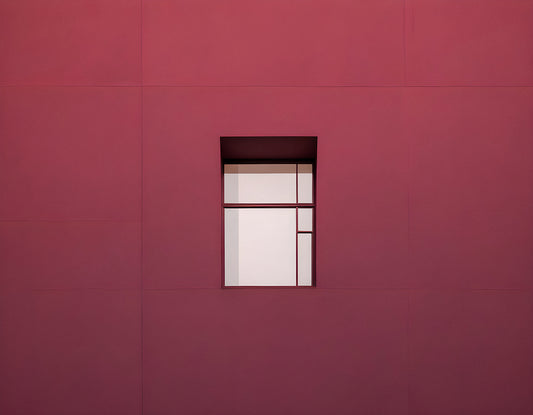 Minimalist architecture featuring a geometric window on a vibrant red wall during bright daylight